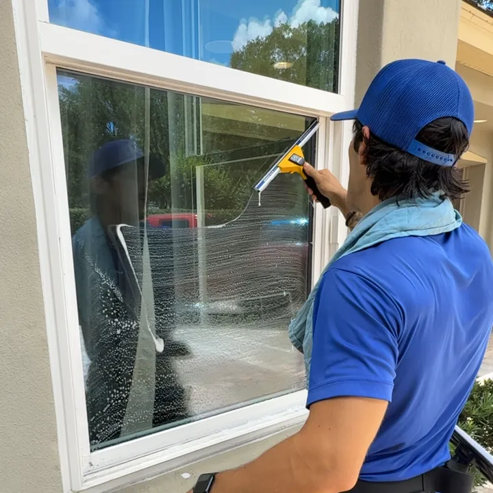 Aquapals pro in a blue cap squeegeeing a window